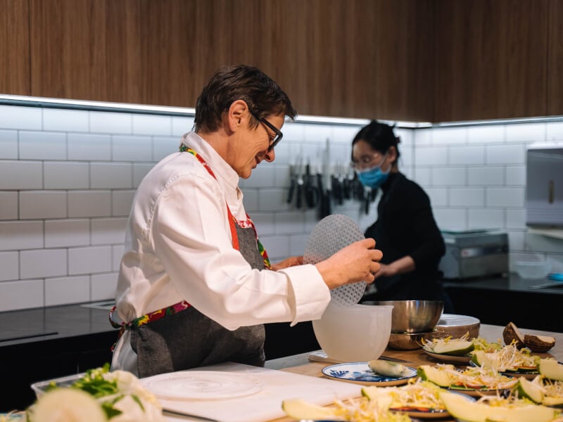 A woman wearing an apron teaching a cooking class.